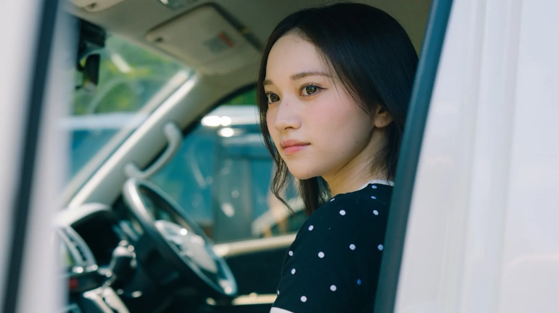 車内から外を見つめる女性を捉えた映像
